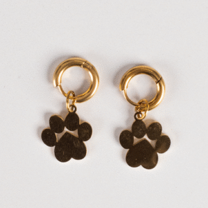 The Earrings - Huggie Paws, two gold hoops each with a dangling paw print charm, are displayed on a plain white background.