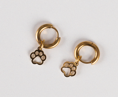 Earrings - Huggie Paws: Gold hoop earrings featuring dangling paw print charms, shown on a simple light background.