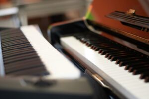 Close-up view of the keyboards of two pianos placed side by side, with blurred background and focus on the white and black keys.