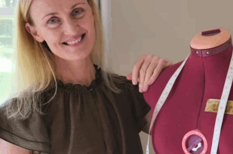 Nikki Hind stands with a red fabric mannequin with a tape measure