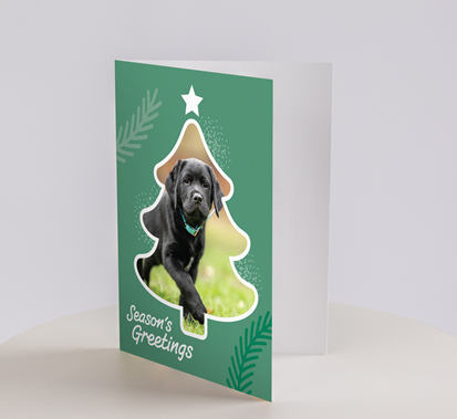 Christmas Cards - Puppies: A festive card featuring a cut-out Christmas tree shape with a black puppy inside, green background, and Seasons Greetings at the bottom.