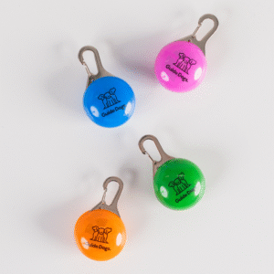 Four round Clip on LED Lights in blue, pink, orange, and green labeled Guide Dogs with a dog logo, arranged on a white surface.