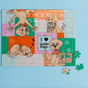 A completed Jigsaw Puzzle featuring a cartoon dog and “I ❤️ Guide Dogs” in the center on a light blue background, with three pieces lying beside it.