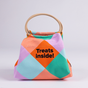 The Lunch Bag is a small, colorful fabric bag with a handle and geometric pattern. The front displays the text Treats inside!.