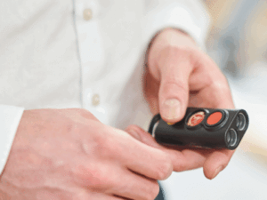 A person holding and pressing a button on a handheld remote assistive tech device.