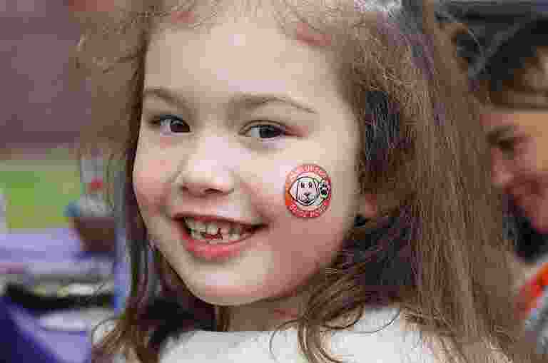 A young child with face paint on its face is smiling at the camera.