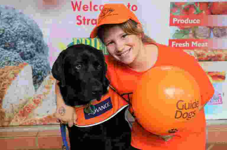 An image of a young girl hugging a yellow Guide Dog.