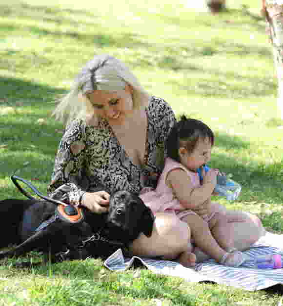 Ebony and Hollie wqith one Ebony's children, sitting on a picnic rug on the grass.