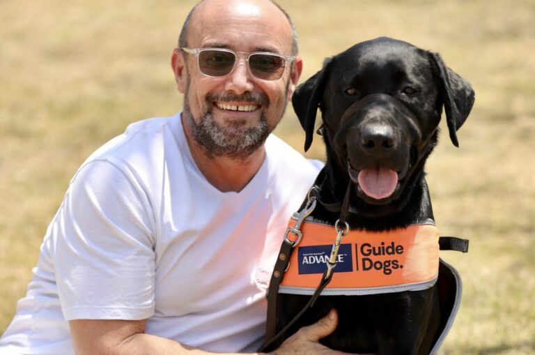 Image of Carlos with a puppy in a training coat.