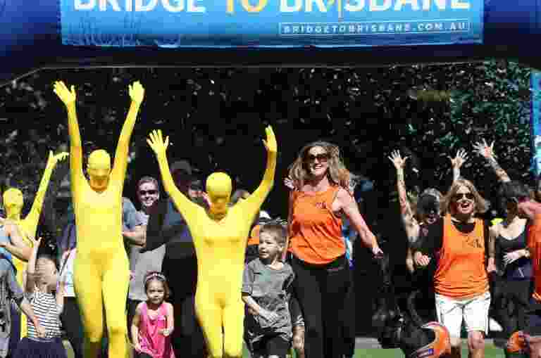 Image of a group running through a Bridge to Brisbane banner.