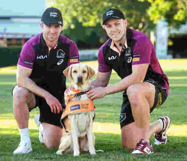 Two Broncos players with puppies