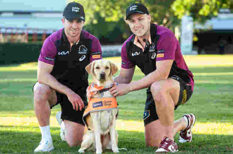 Two Broncos players with puppies