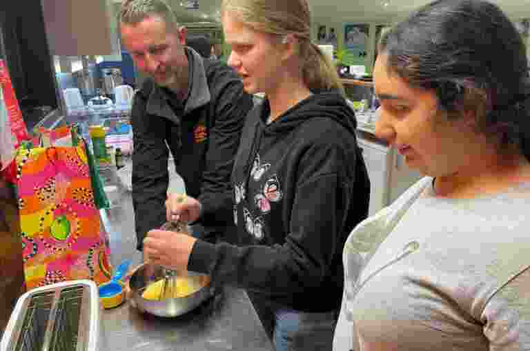 Occupational Therapist, Justin, is pictured working with two students using a whisk in the Guide Dogs kitchen.