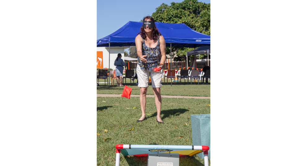 A woman wearing a blindfold is doing a beanbag toss activity.
