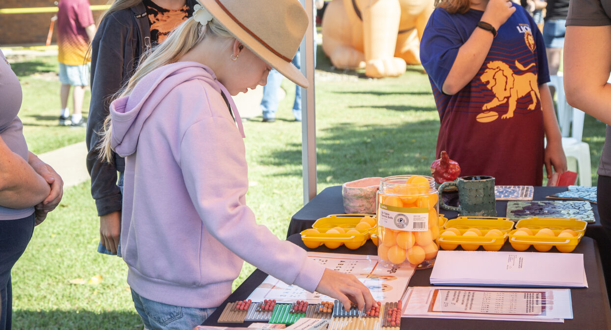 A young girl is standing at a table looking at a chart that displays braille letters.
