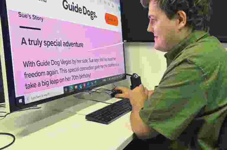 Client, Brent is sitting at a computer in an office. The web page is zoomed in, so the font is larger for him to read.