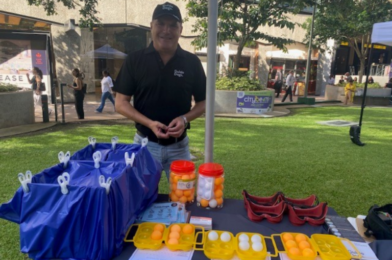 Jeremy standing at a stall with ping pong balls. Smiling at the camera.