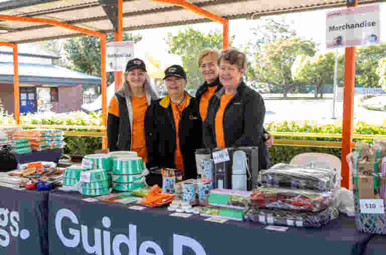 Image shows volunteers in front of a Guide Dogs merch stall.