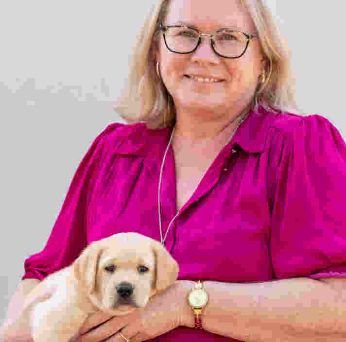 Amanda holding a labrador puppy and smiling at the camera.