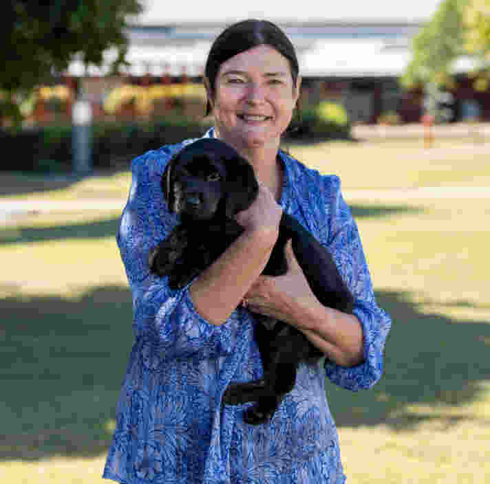 Kerry Cutting smiling at the camera holding a labrador puppy.