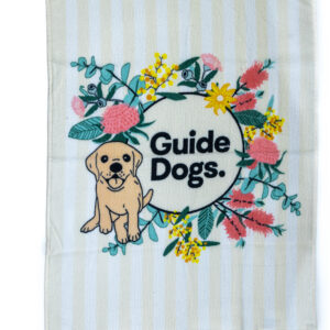 A tea towel with a floral pattern in the centre as well as a Guide Dogs logo with a puppy.