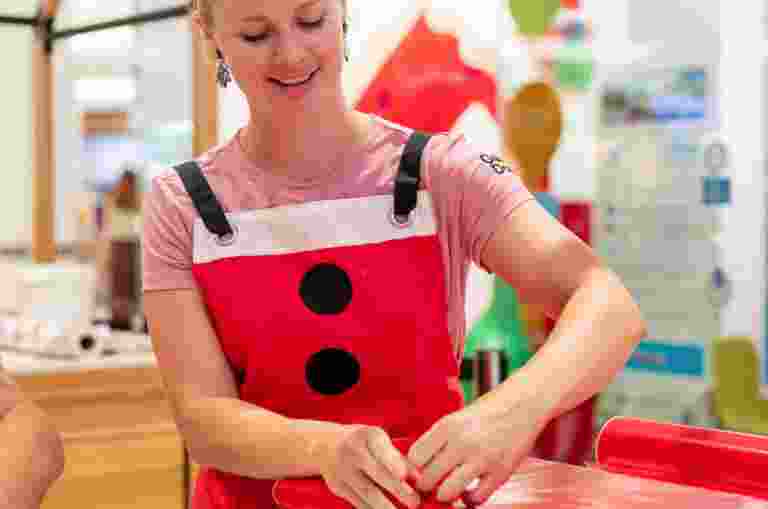 A woman wrapping Christmas gifts, smiling at the camera.