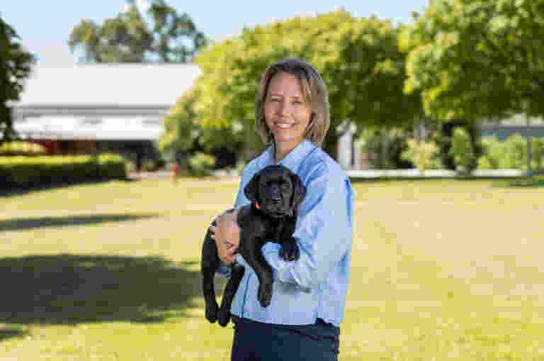 A headshot image of Occupational therapist: Kirsty Jackson, holding a black guide dog, smiling at the camera